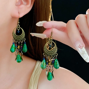 Detail of vintage bronze drop earrings with green turquoise beads and metal leaf charms