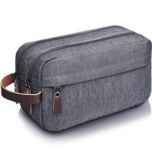 Detail of grey-blue canvas toiletry bag with brown leather accents and dual zippers