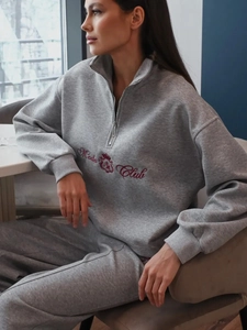 Detail of grey half-zip sweatshirt with red crown embroidery and knitted texture