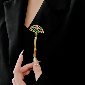 Detailed close-up of an 18K gold fan brooch with pink enamel flowers and pearl tassels