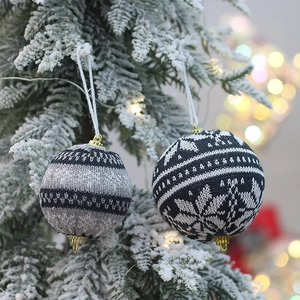 Knitted Christmas tree ornaments with gray stripes and navy snowflake pattern hanging on tree