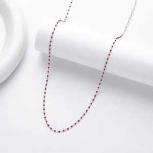 Detailed close-up of s925 silver necklace with delicate red beads on white background