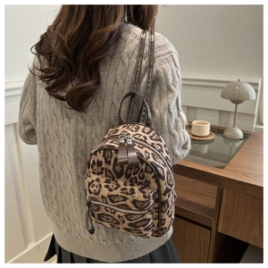 Detail of a mini leopard print backpack with premium leather straps on a grey sweater