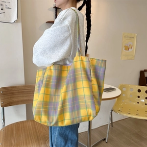 Close-up of a large yellow and purple checkered canvas tote bag worn on a shoulder