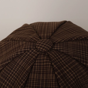 Top detail of retro brown plaid octagonal cap showing fabric texture and button