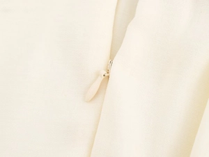 Close-up of invisible zipper and textured beige fabric on this backless summer dress