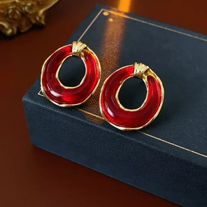 Macro shot of red resin earrings with gold metal frame showing fine craftsmanship