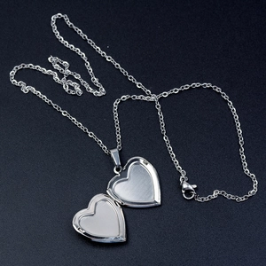 Silver stainless steel heart locket necklace with open photo compartment on black background
