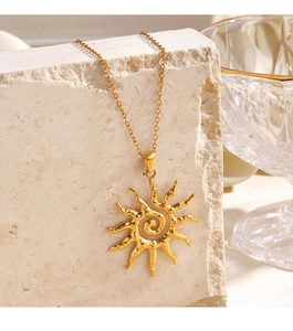 Detail of a golden sun pendant necklace with spiral texture on a beige stone
