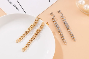 Dettaglio di orecchini a catena oro e argento con ciondoli Luck in stile a nappa lunga