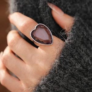 Close-up of a silver ring with a large heart-shaped purple gemstone on a finger