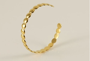 Detail of 18K gold plated stainless steel open bangle with geometric disc link design