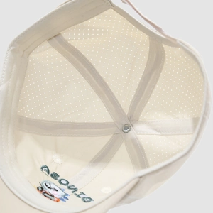 Internal view of beige baseball cap showing breathable laser-cut holes and embroidery