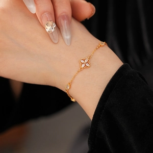 Detail of gold flower bracelet with zircon stones worn on wrist against black velvet