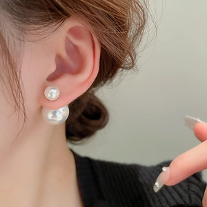 Close-up of elegant double-sided faux pearl earrings worn on ear with 3D effect