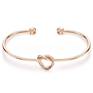 Detail view of rose gold knotted stainless steel open bangle with spherical ends