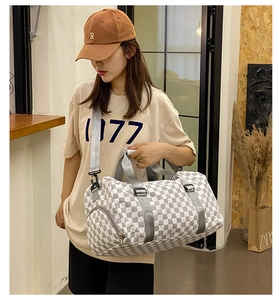 Detailed view of a large capacity checkerboard travel duffel bag held by a fashion model