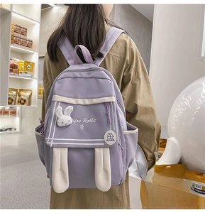 Rear view of a lavender purple school backpack with cute white rabbit ears and plush doll