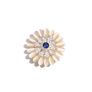 Close-up of a sun flower brooch with white opal petals and a dark blue zircon center