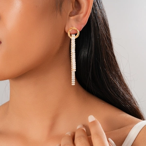 Close-up of gold tassel earring with sparkling rectangular zircons on model's ear
