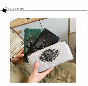 Three crocodile pattern long wallets featuring ornate metal skull hardware in distinct colors