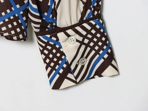 Gros plan du poignet d'une chemise à carreaux avec boutons blancs et coutures précises