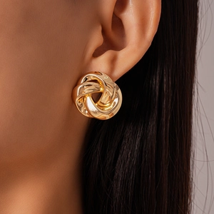 Close-up of golden geometric twisted knot earring worn by a model in a professional shot