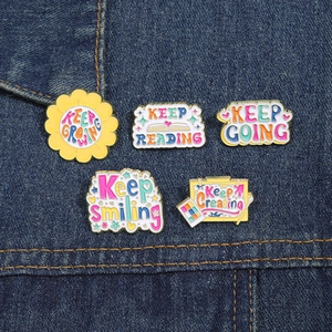 Macro shot of assorted inspirational pins with yellow enamel finish on blue denim jacket