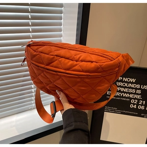 Close-up of orange quilted crossbody bag showing nylon texture and zipper details