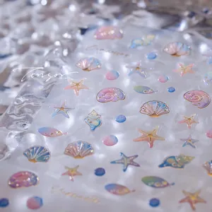 Makroaufnahme von 3D Muschel und Seestern Nagelstickern mit Perlglanz-Effekt