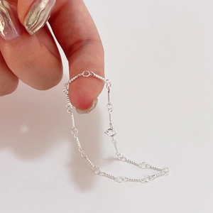 Detailed close-up of a twisted silver rope chain bracelet held to show texture