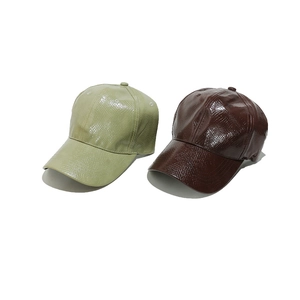 Detail shot of PU leather baseball caps with glossy snakeskin texture in green and brown