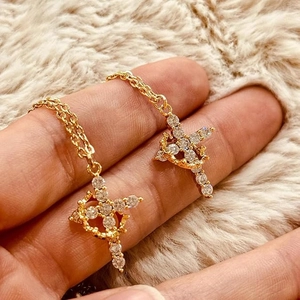 Macro shot of 18K gold crown cross pendant with rotating cubic zirconia stones