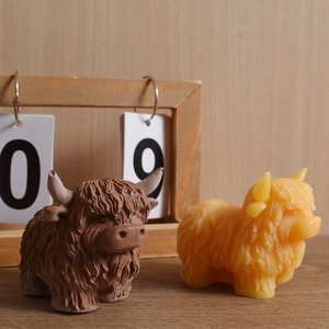 Detailed view of Scottish Highland cow candles in brown and cream yellow colors