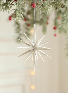 Sparkling white glitter star ornament hanging on a pine branch with festive bokeh lights