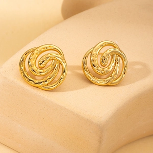 Polished gold spiral flower earrings with textured layers on a minimalist stand