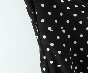 Gros plan détaillé sur la fermeture éclair invisible d'une robe noire à pois blancs