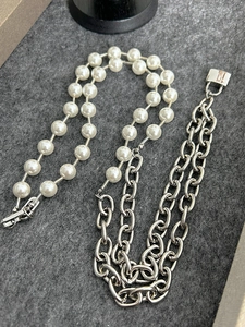 Detail of pearl and silver chain necklace featuring a square metal clasp and logo