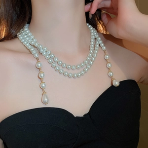 Dettaglio di una collana di perle multistrato con ciondolo a goccia d'acqua dorata