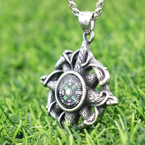 Compass pendant necklace in vintage stainless steel on a textured green background