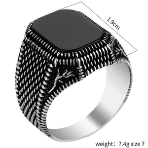 Vintage men's silver ring with square black onyx and retro carved texture on white background