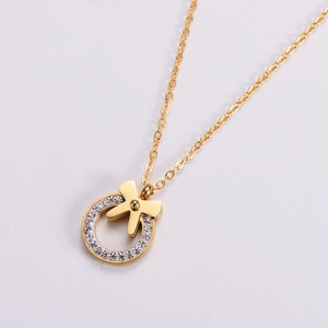 Golden bow necklace with a round rhinestone pendant shown from a side diagonal view