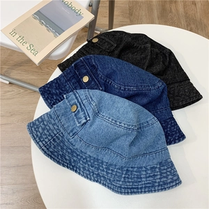 Flat lay of denim bucket hats in light blue, dark blue, and black with metal button detail