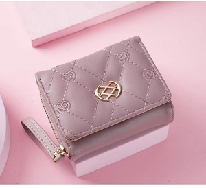 Detail of quilted leather wallet in dusty rose with golden clasp and floral embroidery