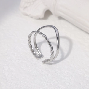 Detail of silver double-layered open ring with twisted texture on stone background