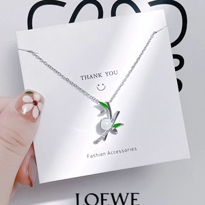 Detail of bamboo pendant necklace with green enamel leaves, white pearl, and silver chain
