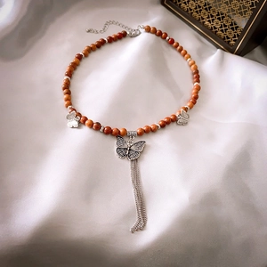 Détail du collier de perles en ébène vintage avec pendentif papillon et pompons