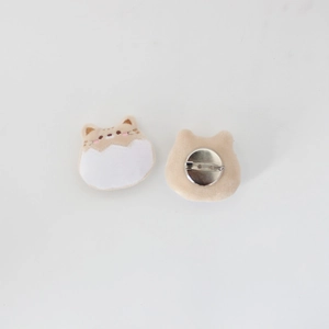Detail of plush cat brooch showing cute embroidered face and secure metal pin backing