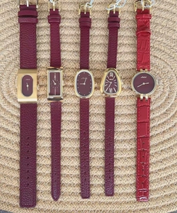 Detailed view of various wine red leather watches with gold cases and diverse dials