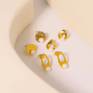 Three pairs of vintage gold titanium steel earrings with white pearls on geometric background